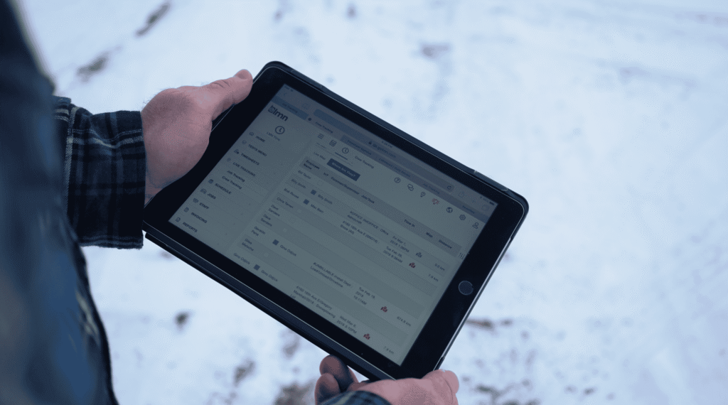 Image of a person holding a tablet showing LMN Landscaping business software.
