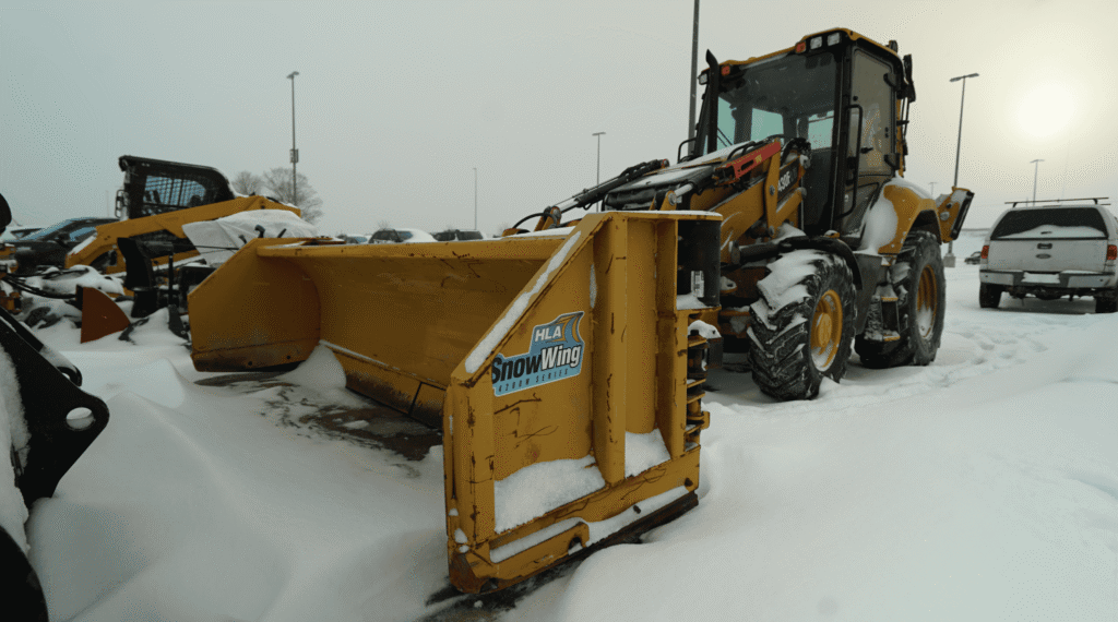 Photo of a parked front-end loader in a snow-covered parking lot.