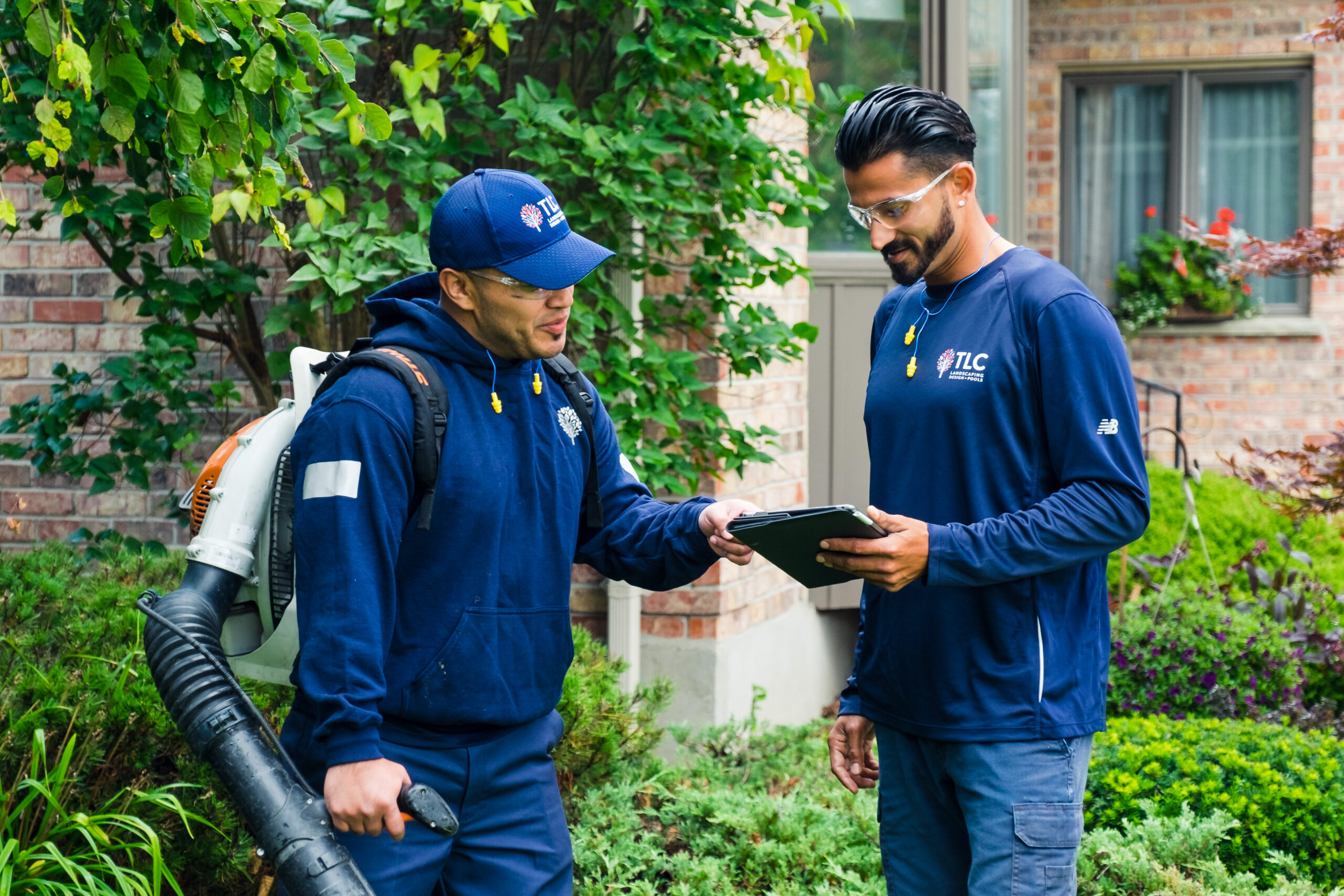 Two landscape professionals standing outside looking at a tablet.